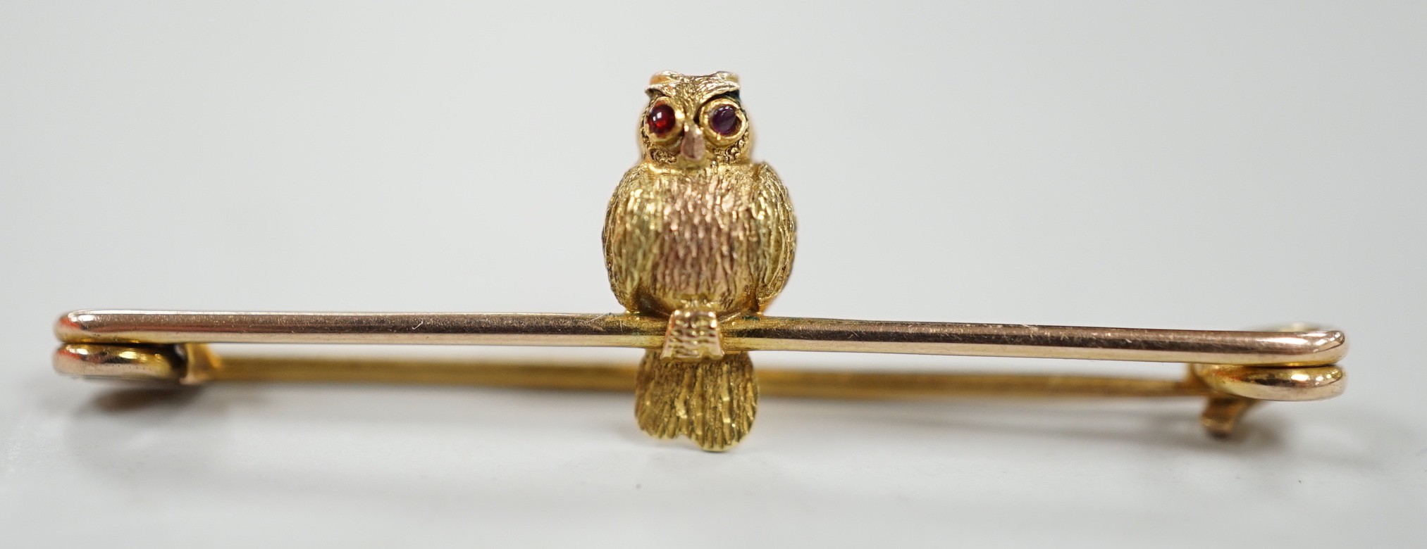 A mid 20th century two colour 9ct owl bar brooch, with cabochon eyes, 38mm, gross weight 1.3 grams.